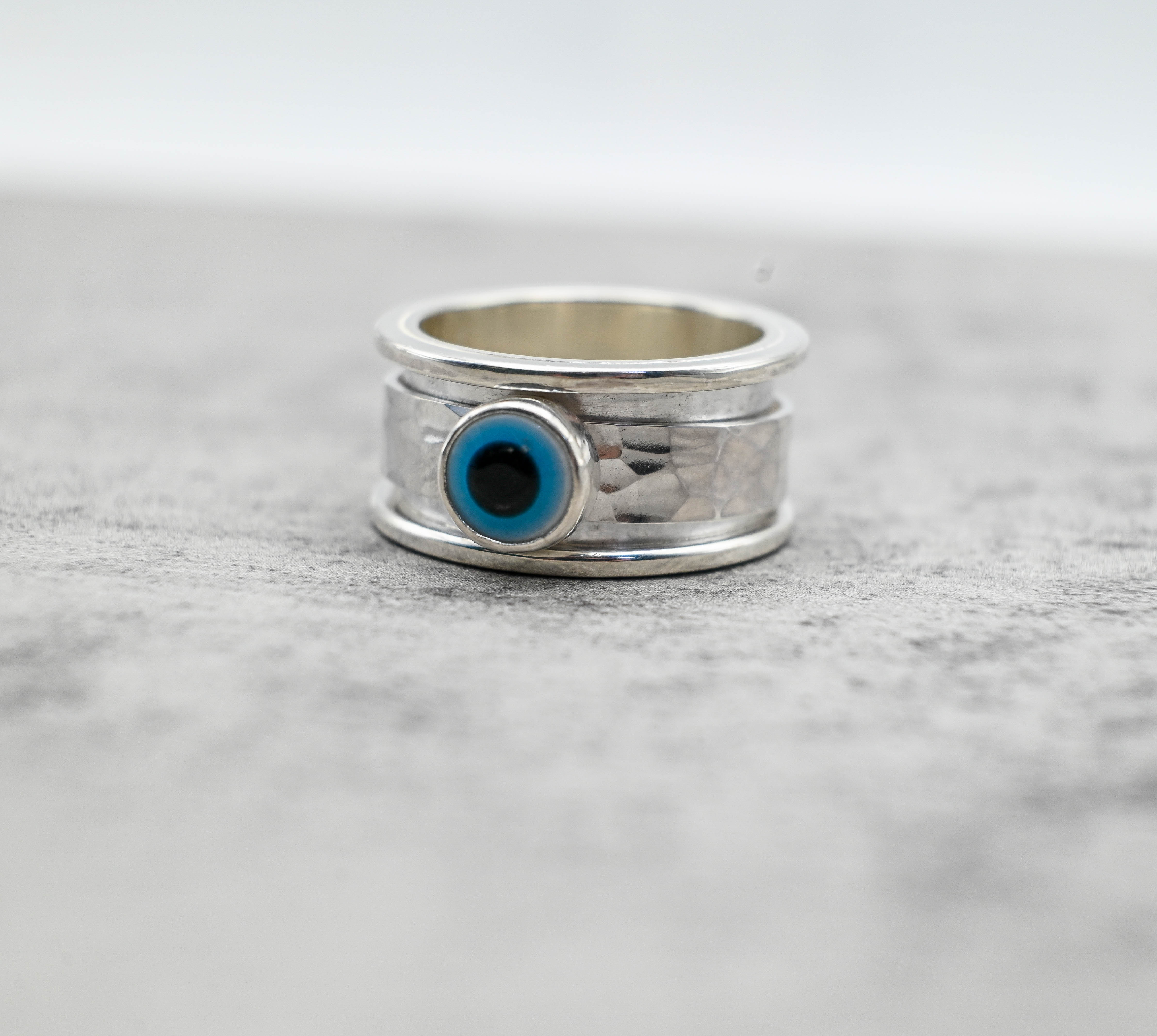 Spinner δαχτυλίδι ασήμι με evil eye μπροστινή όψη σε γκρι φόντο