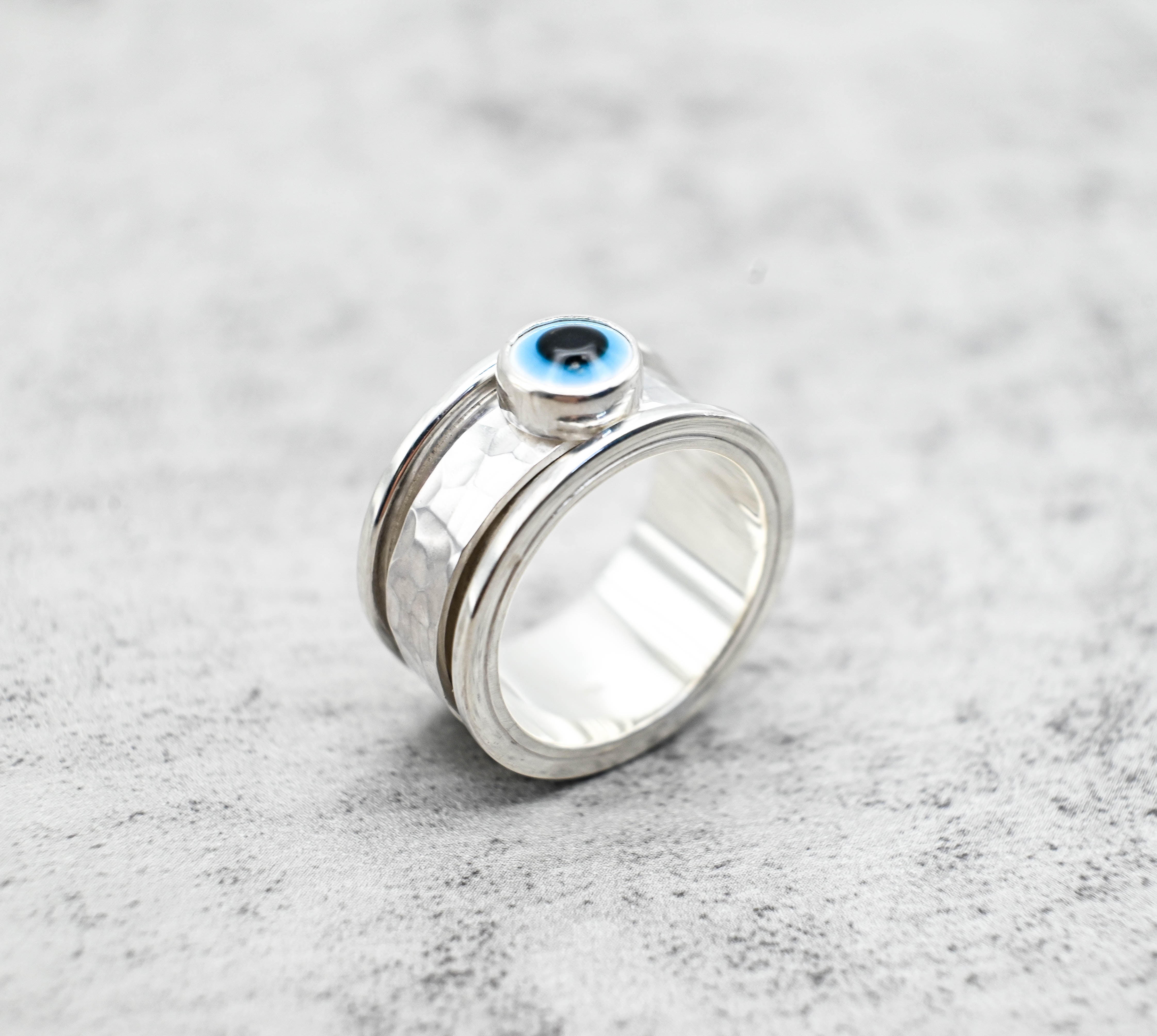  Spinner δαχτυλίδι ασήμι με evil eye πλάγια όψη αριστερά σε γκρι φόντο