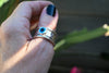 Spinner δαχτυλίδι ασήμι με evil eye φορεμένο σε δάχτυλο γυναικείο χέρι εξωτερικός χώρος