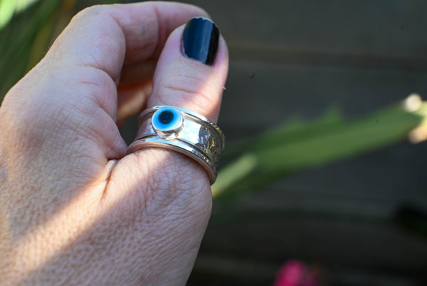 Spinner δαχτυλίδι ασήμι με evil eye φορεμένο σε δάχτυλο γυναικείο χέρι εξωτερικός χώρος